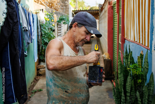 Obraz na płótnie Middle aged man preparing paint while restoring a bicycle in a modest residential alley