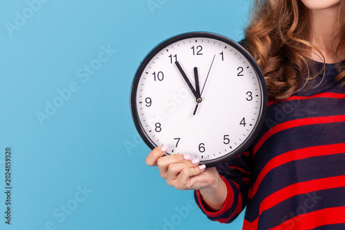 Anonymous user holding alarm clock to show deadline pressure or time management concept for busy workers isolated over blue background with copy space