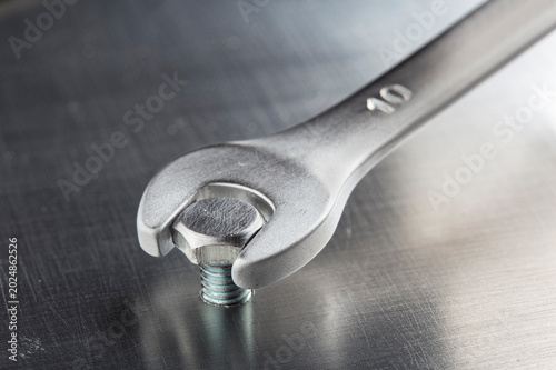 Fotografie wrench tightens bolt in metal aluminum plate