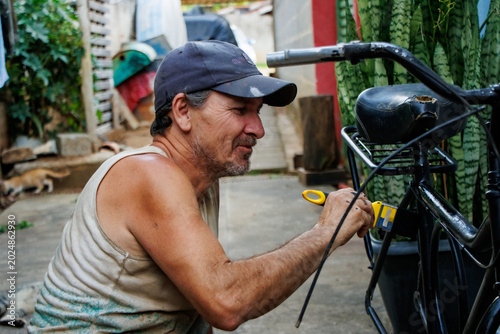 Foto Smiling middle aged man restoring and painting a bicycle frame outdoors in a modest residential backyard
