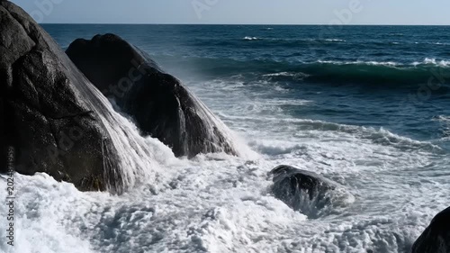 Ocean waves crashing against rocky coastline creating splashing water effect