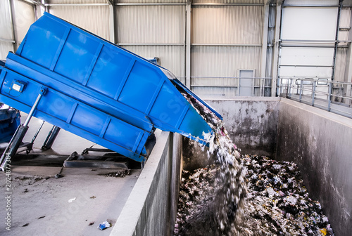 Sustainable waste management facility in action, with an industrial compactor efficiently emptying discarded materials for modern recycling success