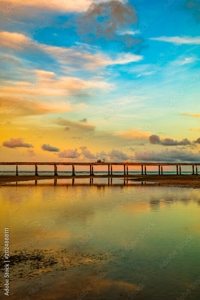 Fototapeta premium A tropical beach scene at sunset featuring a soft gradient sky of blue, yellow, and orange hues