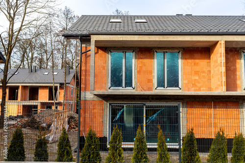 Fotografía Newly built brick duplex house with unfinished facade, roof tiles, construction