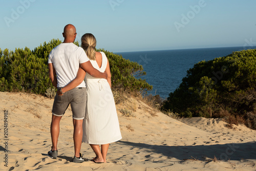 Pareja abrazada mirando el mar.
