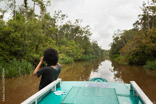 Paisaje de río en Borneo con chico haciendo foto desde el barco.