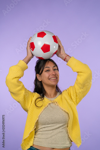 Young woman balancing soccer ball, smiling