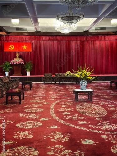 Foto An opulent ceremonial hall featuring a large patterned red carpet, crystal chandeliers, and classic wooden paneling