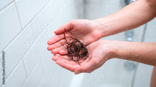 Woman holding a clump of dark hair in her hands after showering