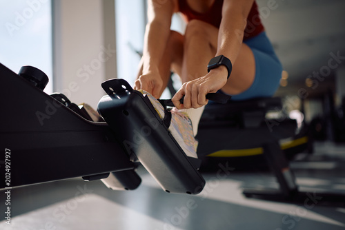 Foto Close up of sportswoman working out on rowing machine in health club