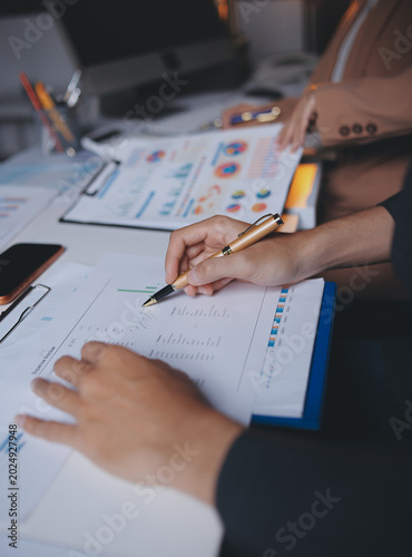Two business people talk project strategy at office meeting room. Businessman discuss project planning with colleague at modern workplace while having conversation and advice on financial data report.