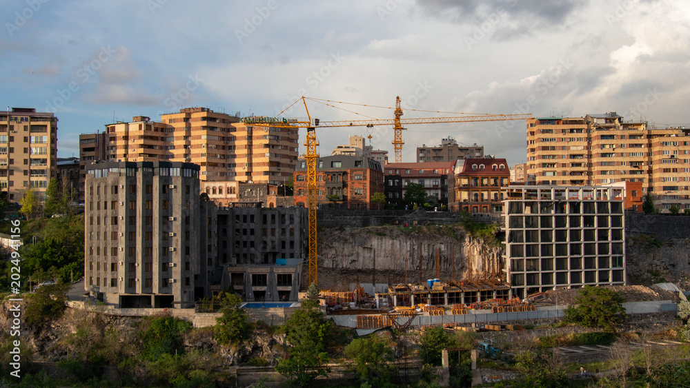 Fototapeta premium Construction crane working on an urban development project in Yerevan, Armenia, highlighting the mix of modern and historical architecture.