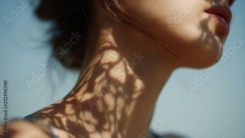 女性の首元に植物の影が映っているクローズアップ。自然光を活かしたナチュラルな雰囲気のポートレート素材