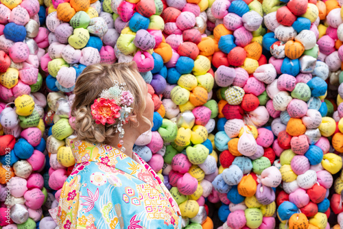 Foto Woman dressed in a kimono looks at Kukurizaru color ball ema at Yasaka Koshin-do