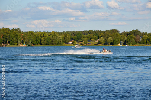 Cuadro en lienzo Man riding a jet ski on a calm lake on a sunny summer day