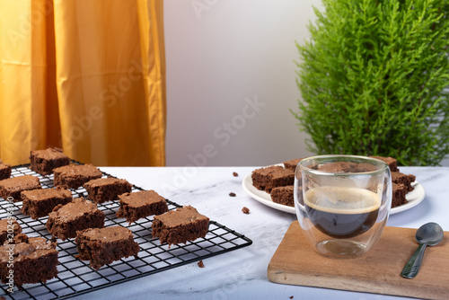 A cup of espresso and a chocolate brownie cut into pieces.