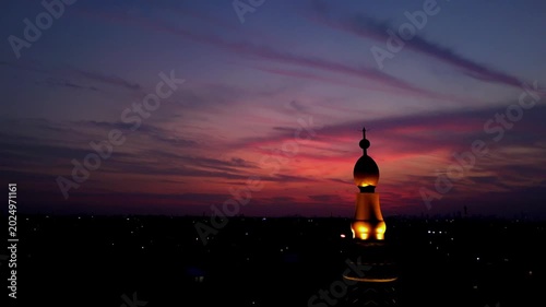 Beautiful sunset sky with purple clouds over a silhouette mosque dome tower at dusk