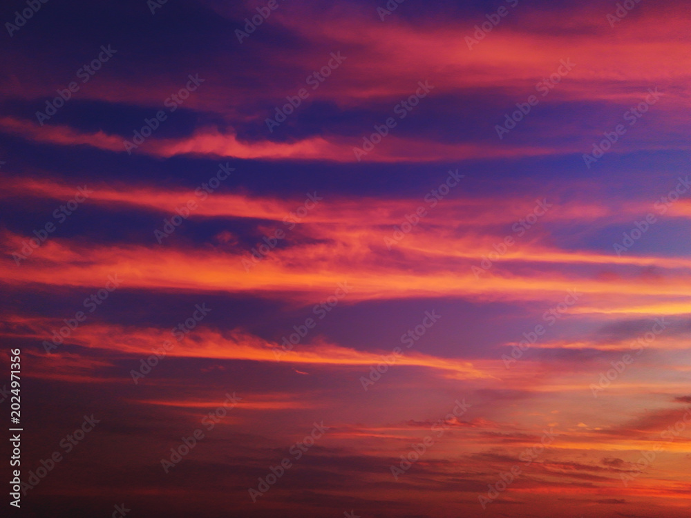 Fototapeta premium Beautiful dramatic sunset sky with vibrant orange pink and purple clouds over a dark twilight horizon