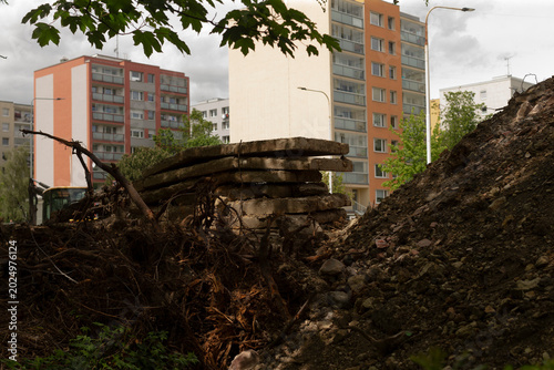 Tableau sur toile Stacked slabs and soil mound under cloudy sky, staging area tucked behind housin