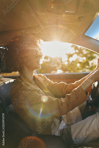 Photography Woman driving a car at golden hour with retro film color, warm sunlight glow and soft focus