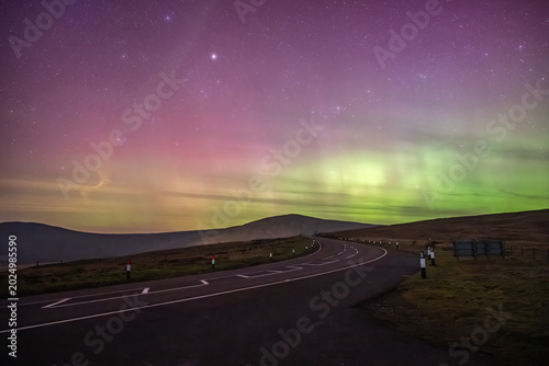 A panoramic night landscape of the Isle of Man’s Mountain Road winding through the uplands towards the distant peak of Snaefell mountain.