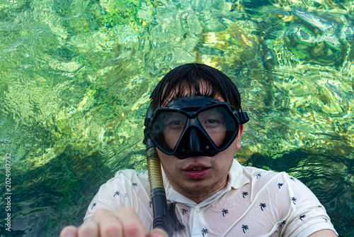 Asian man snorkeling near boat during family summer vacation in tropical area of ​​belitung island, indonesia.