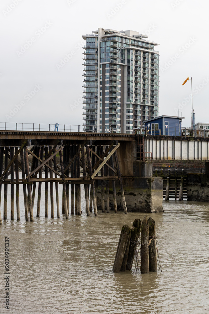 Fototapeta premium Modern Riverside Condominium Tower by a Timber Pier in New Westminster, Vancouver, BC, Canada