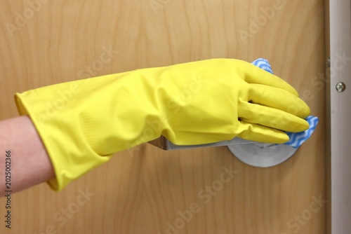 Woman hand in glove with sponge cleaning a handle for carrying. Building or house cleaning and surface disinfection. Metal door handle disinfection and prevention of virus.