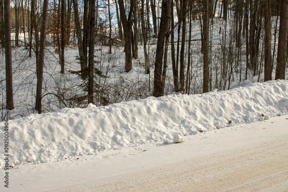 Obraz premium A plowed snowbank by the road in the winter forest