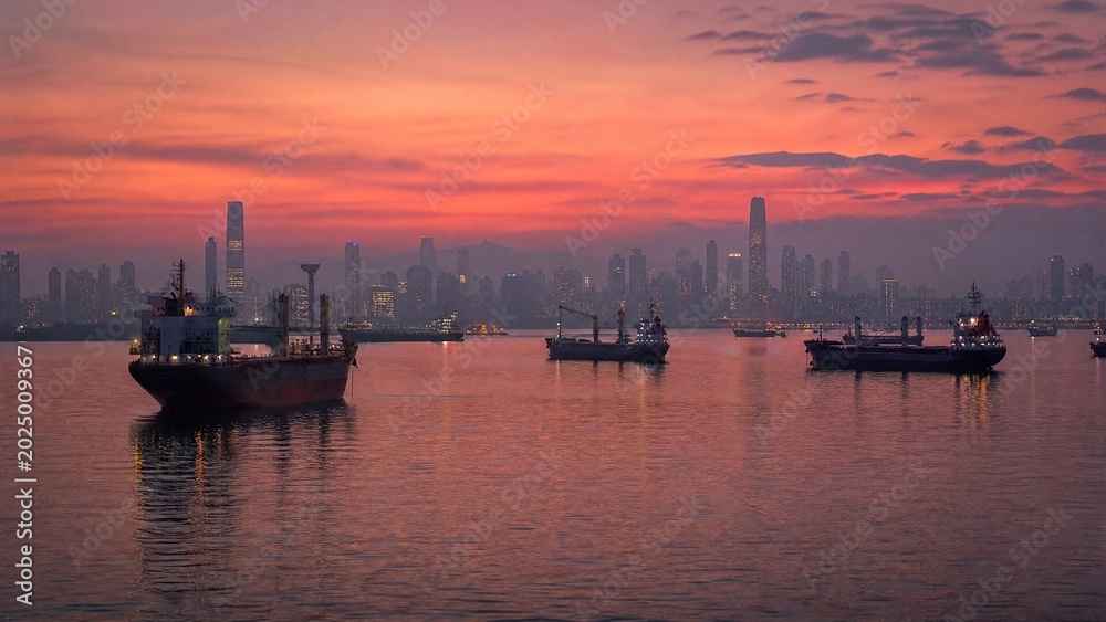 Obraz premium roadstead. Cargo ships anchored in calm roadstead at dusk, silhouetted against hazy city skyline. mobility guides, transit brochures, designed for transport & logistics marketing.
