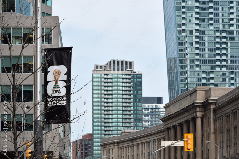 Fototapeta premium Vertical banner promoting FIFA World Cup 2026 attached to street pole in urban downtown Toronto Ontario area with modern office buildings and Union Station in the background, May 17 2026