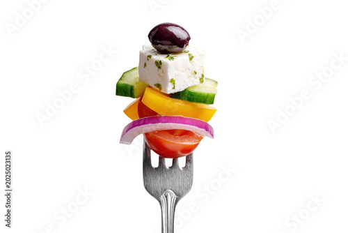 A fork with a skewer of greek salad ingredients including feta cheese, olive, cucumber, tomato, yellow pepper, and red onion isolated on transparent background