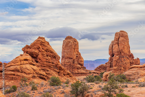 Φωτογραφία Three towering red sandstone formations stand against a cloudy sky
