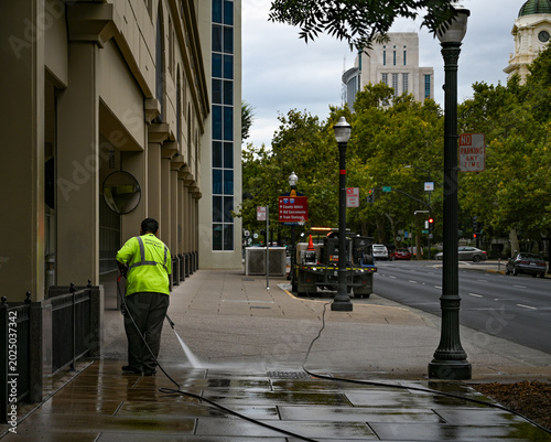 Fotografie City sanitation worker power washing a public sidewalk in downtown Sacramento Ca