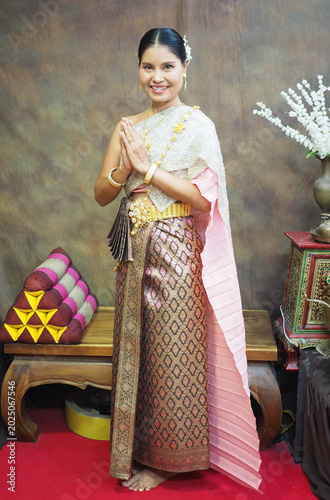 Cuadro en lienzo A Thai woman in traditional Thai dress stands smiling and clasping her hands together in a respectful greeting at Wat Chaiwatthanaram in Ayutthaya Province, Thailand