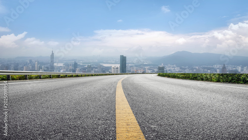 Curved asphalt highway overlooking distant city skyline