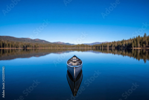 Single modern canoe floating on a calm lake under blue sky