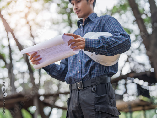 Foto Asian construction engineer reviewing blueprint for building project planning at