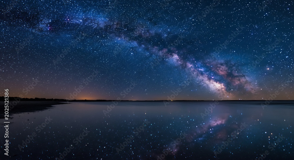 Obraz premium 夜空いっぱいに広がる無数の星々が息をのむほど美しく輝き雄大な天の川が幻想的に流れる静かな水面に神秘的な光景を映し出す壮大な夜景