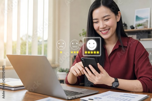 Smiling woman holding a smartphone while working at a desk with a laptop