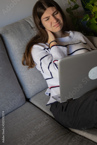 Canvas-taulu Young woman experiencing neck pain and displeasure while working remotely from h