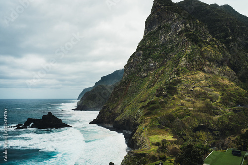 Εκτύπωση καμβά Dramatic Coastal Landscape with Steep Green Cliffs and Turbulent Ocean Waves Und