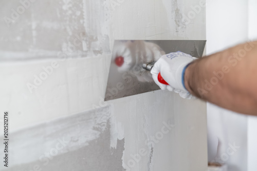 Canvas-taulu Professional applying a smooth finishing coat to drywall using a stainless steel trowel