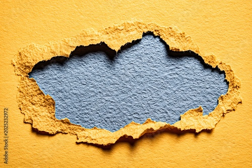Torn ripped yellow paper hole on blue background