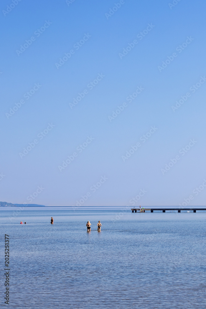 Obraz premium View of a lake with people bathing on a sunny summer day