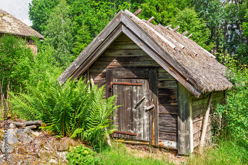 Tableau sur toile Wooden shed by a lush green forest a sunny summer day