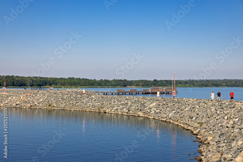 People walking on a stone pier in the sunshine