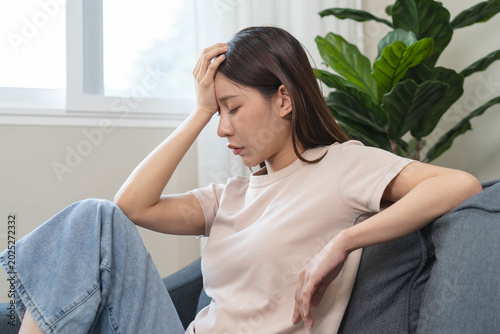 Asians female in stressed expression sitting on the sofa in the house.