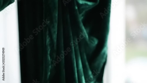 Close-up of a hand touching and revealing a green velvet curtain.