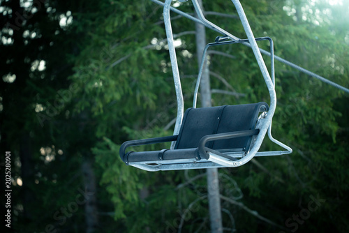 Chairlift elevated passenger ropeway. Empty chair lift bench. Ski station resort with chairlifts for skiers, snowboarders. Ski slope, piste, run or path down a mountain for snow skiing, snowboarding.